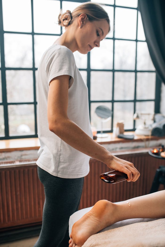 portfolio-img-04 A woman pours oil for a calming massage in a peaceful indoor setting.